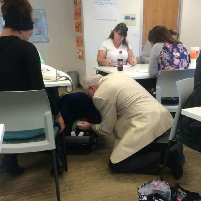 Profesor arrodillado dando de comer a bebé