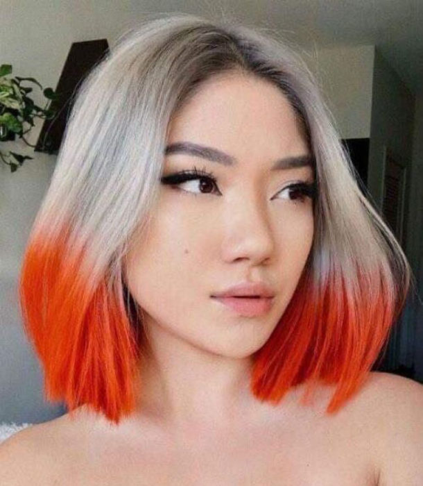 Chica con el cabello teñido en platinado con las puntas en color naranja