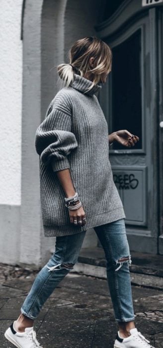 Chica usando suéter holgado color gris, con jeans y tenis blancos