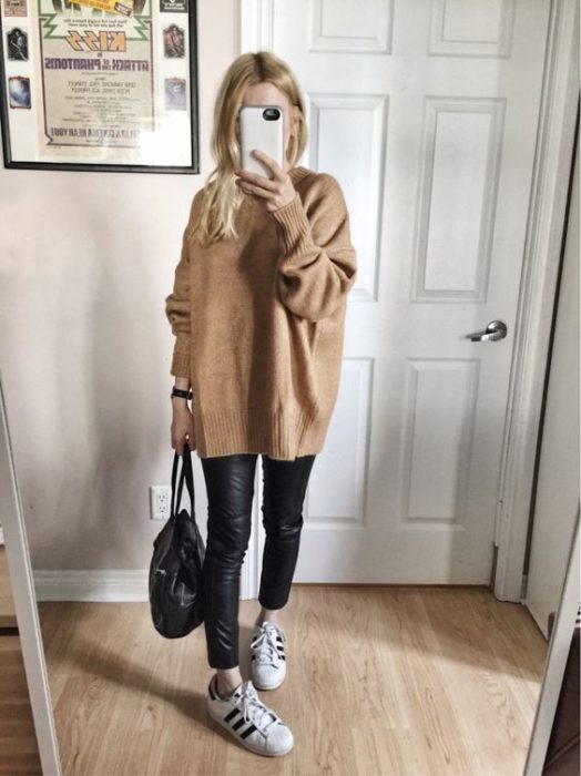 Chica usando suéter holgado color camel, con leggings negros y tenis