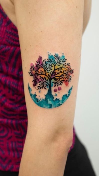 Tatuaje del árbol de la vida y fondo de diferentes colores, sobre el antebrazo