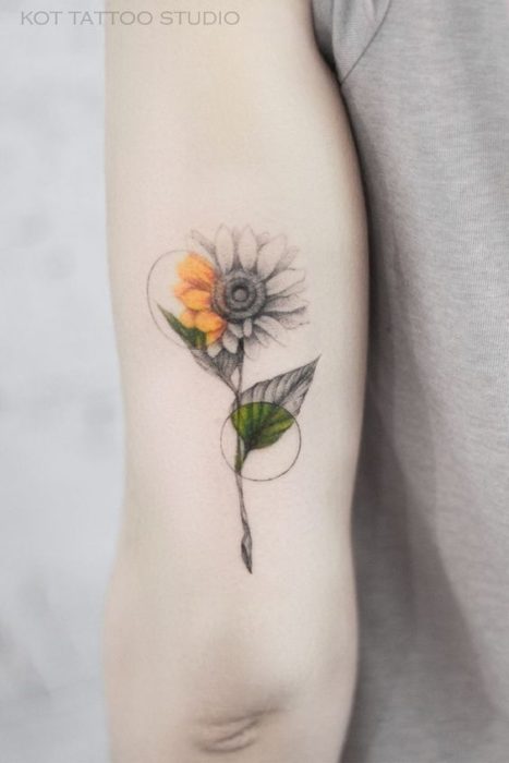 Tatuaje detrás del brazo de un girasol en blanco y negro con dos círculos que denotan los colores propios del girasol