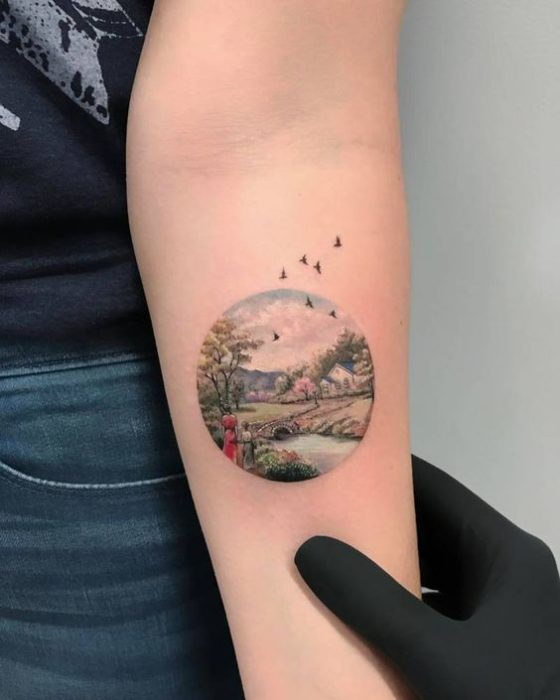 Tatuaje sobre el antebrazo donde está el paisaje de un río y naturaleza