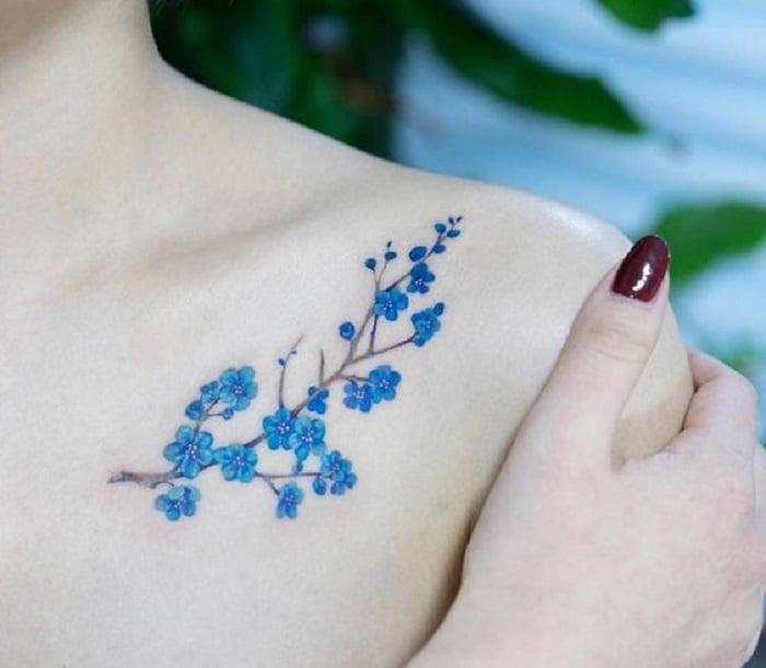 Tatuaje de flores azules debajo de la clavícula