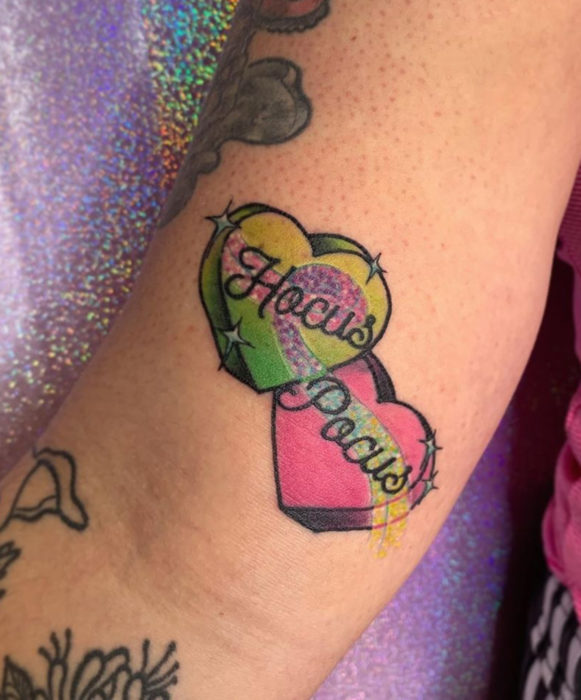 Tatuajes de la película de brujas Hocus Pocus; pastillas de corazones de colores verde y rosa con glitter; tatuaje en el brazo