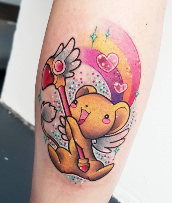 Tatuaje de Sakura Card Captor con colores vivos, Kero con la llave del sello, arcoíris y corazones, en la pierna