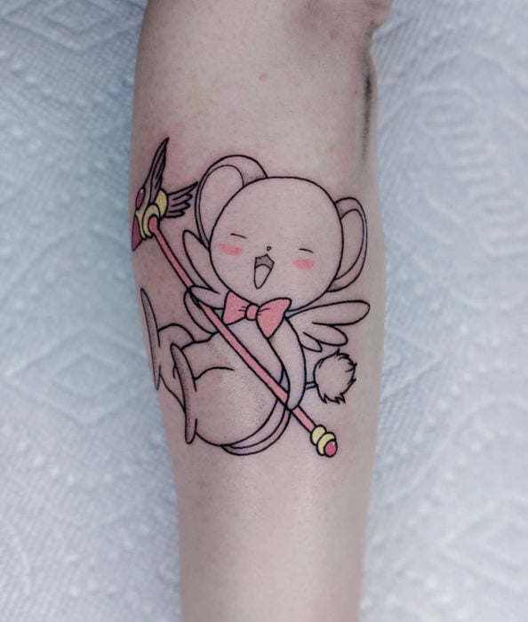 Sakura Card Captor Tattoo auf dem Arm, Kero in schwarzen Linien, mit rosa Siegelschlüssel