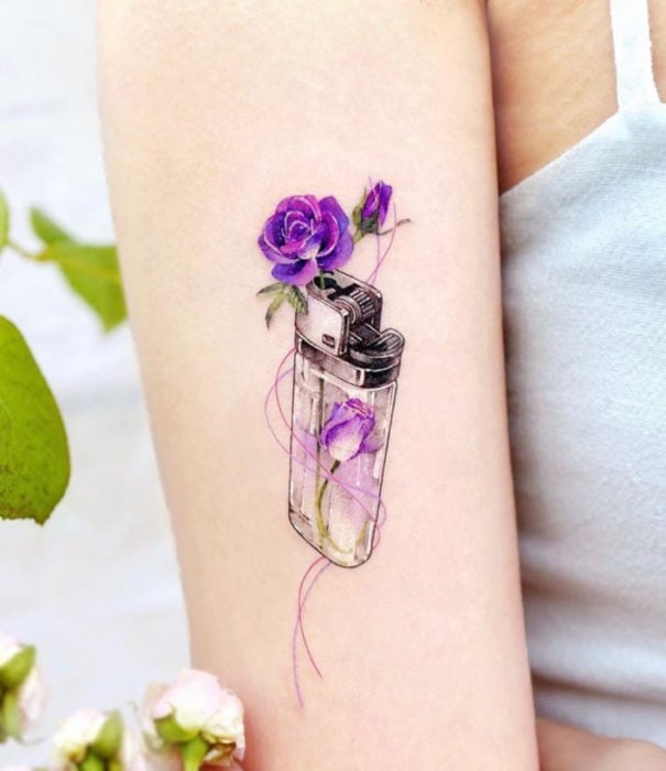 Diseños bonitos de tatuajes de acuarelas; tatuaje de encendedor con flor morada en el brazo