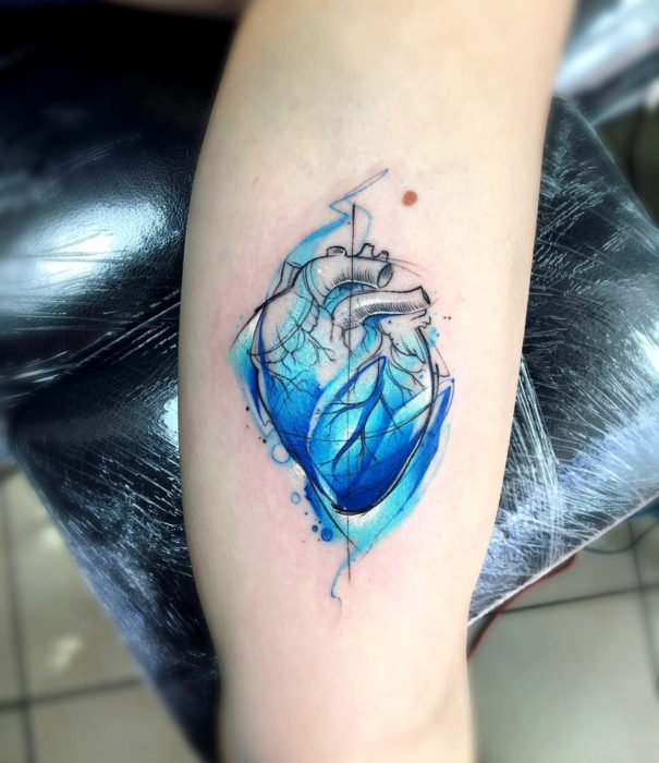 Diseños bonitos de tatuajes de acuarelas; tatuaje de corazón azul realista en el brazo