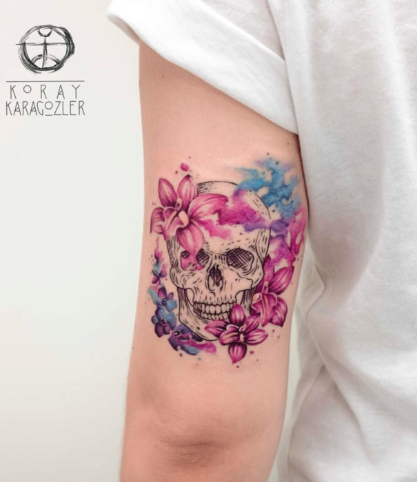 Diseños bonitos de tatuajes de acuarelas; tatuaje de calavera cn flores en el brazo