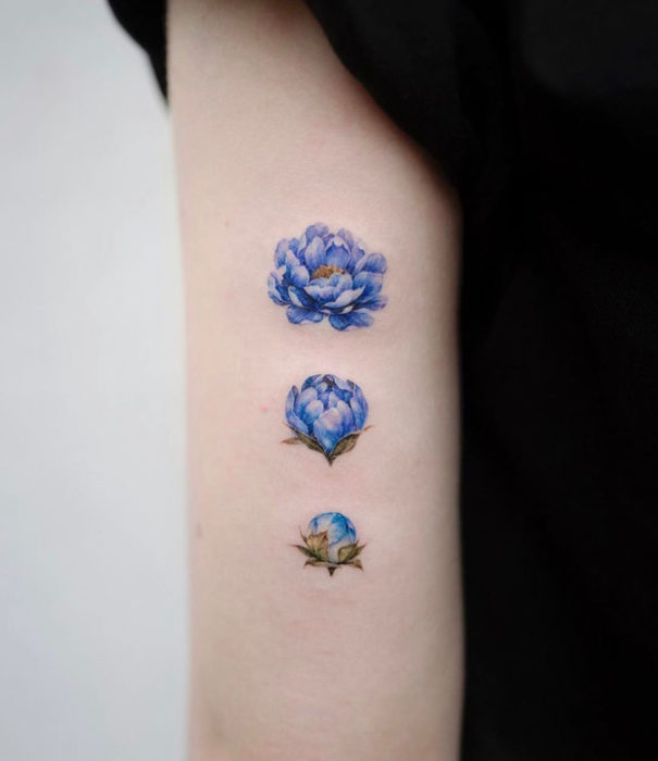 Diseños bonitos de tatuajes de acuarelas; tatuaje de flores azules en el brazo