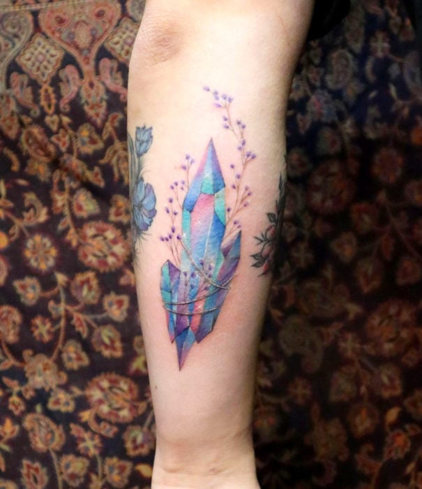 Diseños bonitos de tatuajes de acuarelas; tatuaje de cristales de colores pastel en el brazo