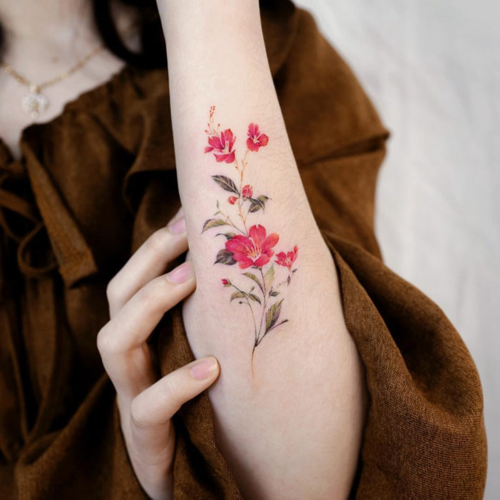 Tatuaje mini, pequeño de flores femeninas rojas en el antebrazo