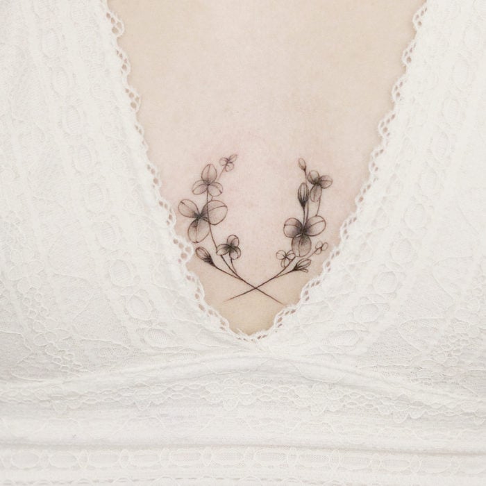 Tatuaje mini, pequeño de flores femeninas en el pecho