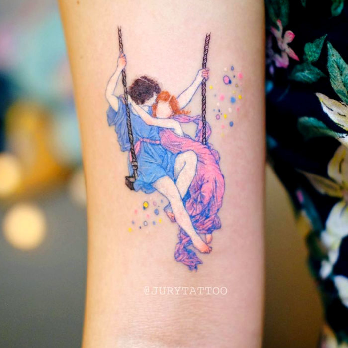 Tatuadora hace tatuajes bonitos, delicados y femeninos que brillan; tatuaje de pintura de Pierre Auguste Cot, La primavera, pareja en un columpio, minimalista en colores rosa y azul pastel en el brazo