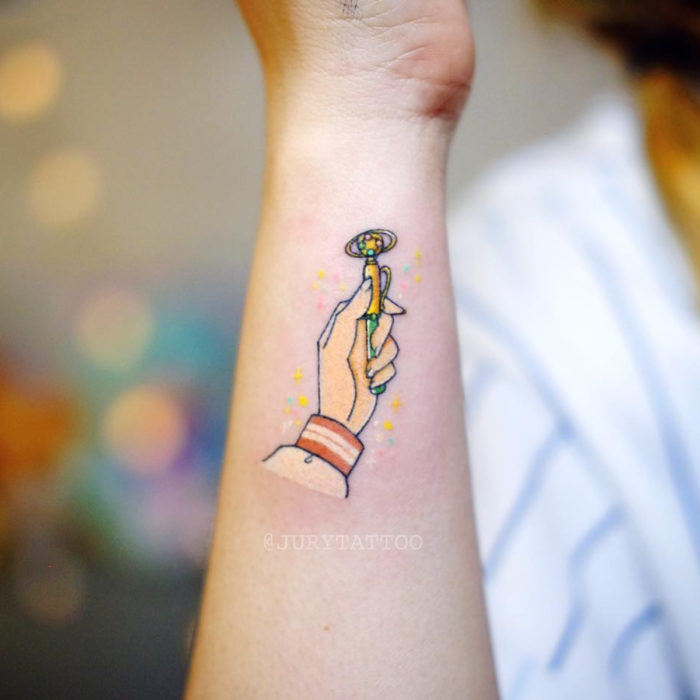 Tatuadora hace tatuajes bonitos, delicados y femeninos que brillan; tatuaje de Sailor Júpiter transformándose, Sailor Moon, en la muñeca