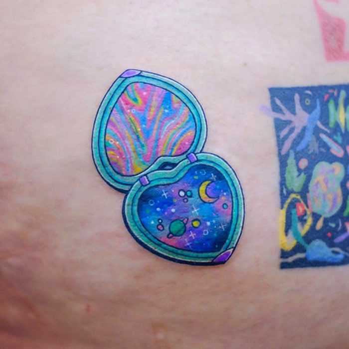 Tatuadora hace tatuajes bonitos, delicados y femeninos que brillan; tatuaje de espejo de mano con universo y planetas