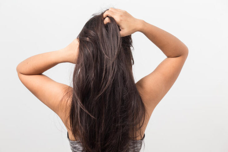 Chica de cabello castaño largo masajeando su cabeza