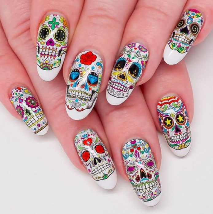 Uñas inspiradas en Día de Muertos con diseño de calaveras en cada uno de los dedos