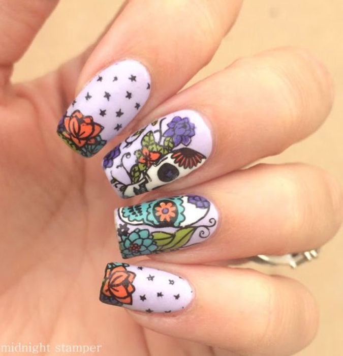 Uñas inspiradas en Día de Muertos con diseño de calaveras con flores de cempasúchil