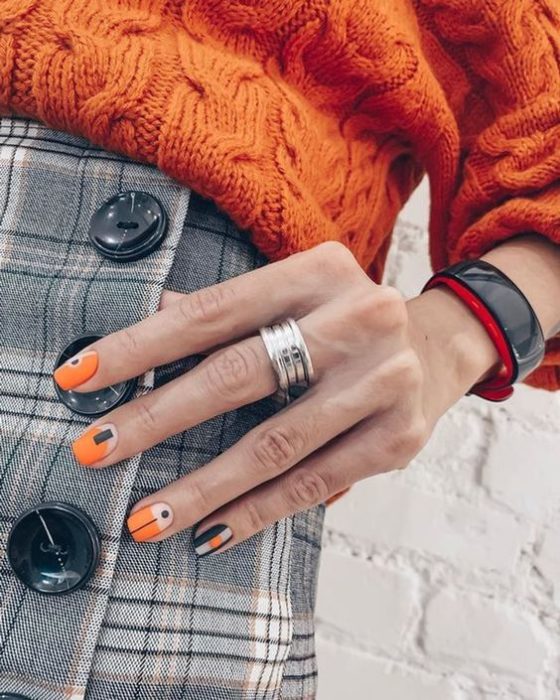 Manicura con detalle geométrico en color naranja y negro