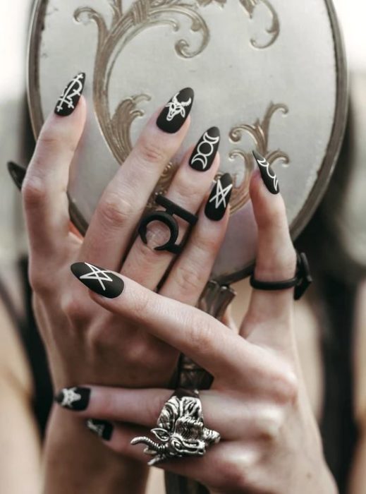 Uñas inspiradas en Halloween con diseño de símbolos de brujas