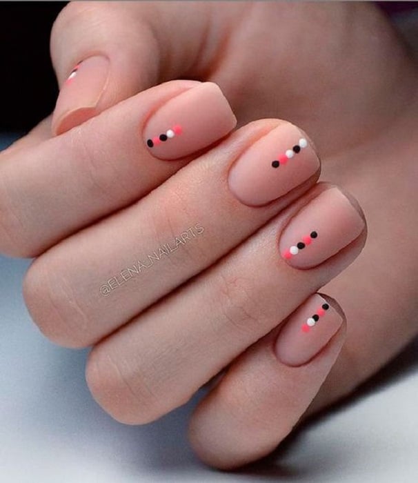 Diseño de manicura en uñas cortas en fondo nude con puntos de colores en la punta