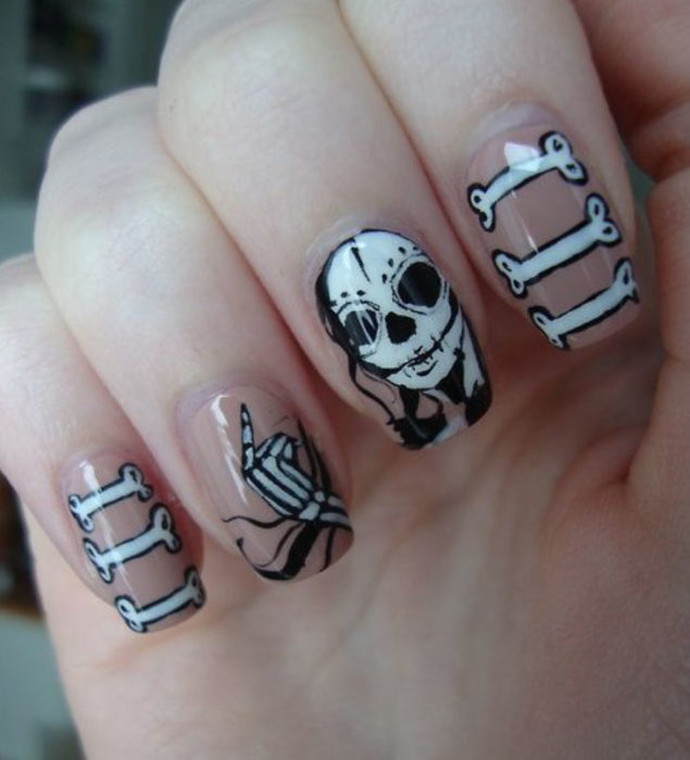 Uñas inspiradas en Día de Muertos con diseño de calavera y huesitos con fondo transparente y color blanco y negro