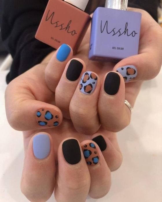 Manicura en diseño animal print en colores azules y negros con diseño en dedos pulgar y medio