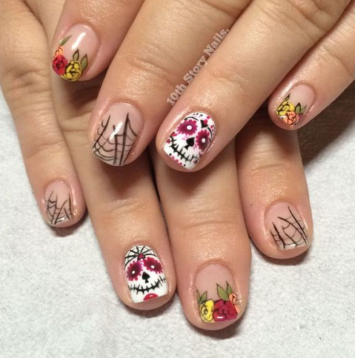 Uñas inspiradas en Día de Muertos con diseño de calaveras, con flores y fondo transparente