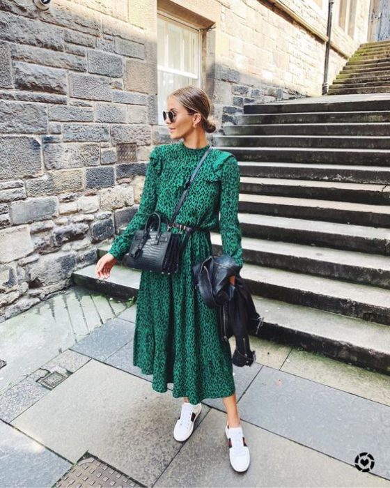 Chica rubia con cabello recogido en chongo bajo y vestido verde largo con tenis blancos