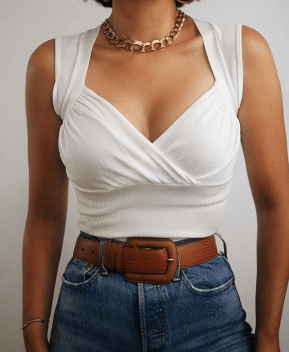 chica morena usando un top blanco con tirantes anchos y cuello en V, cinturón café y jeans a la cintura