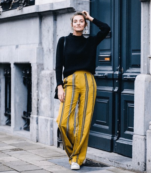 chica de cabello castaño usando un suéter negro con pantalón amarillo de rajas azules con blanco