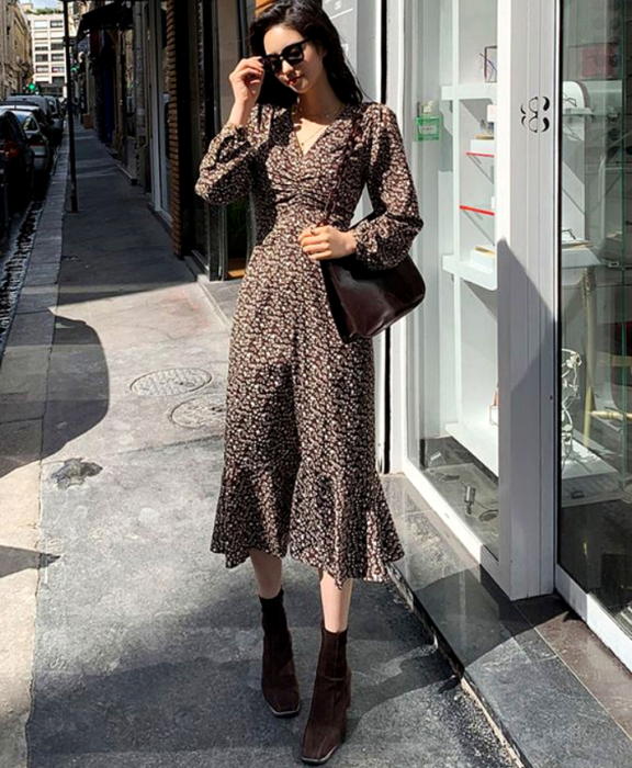 chica de cabello castaño largo usando lentes de sol, vestido café con flores, bolso café y botines cafés de cuero con tacón