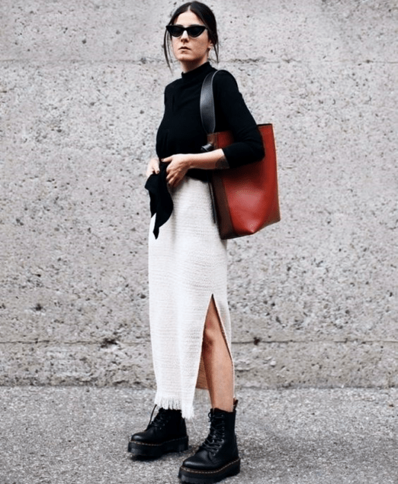 chica de cabello oscuro usando lentes de sol, suéter negro, bolso rojo, falda larga de color blanco, botines negros de suela gruesa