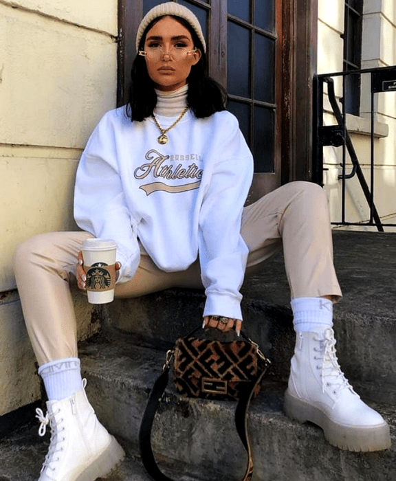 chica de cabello castaño usando lentes, beanie gorro beige, sudadera blanca, pantalones beige, botines blancos de suela transparente y bolso café fenti