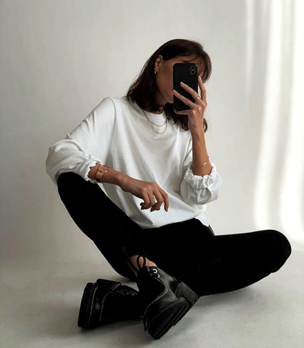 chica de cabello castaño usando una sudadera blanca, leggings negros y zapatos de plataforma negros