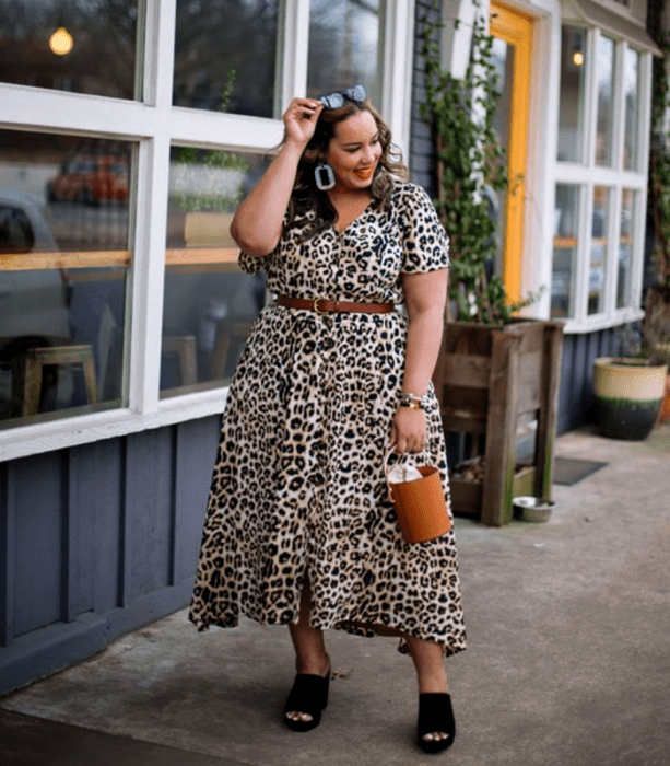 chica curvy de cabello claro usando lentes de sol, vestido largo de animal print, tacones negros y bolso bucket café de cuero