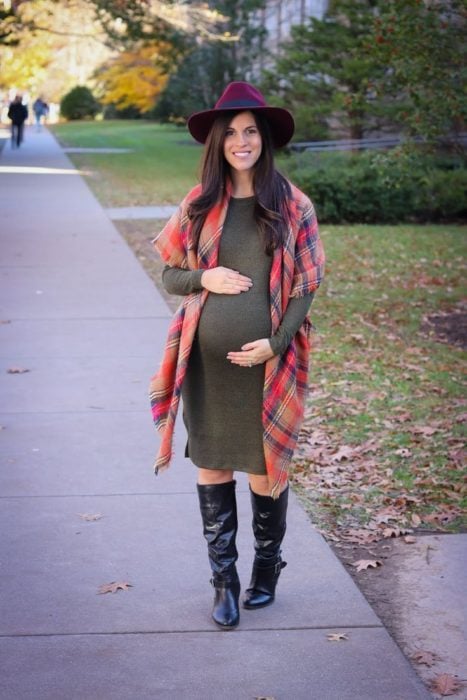 Chica usando un outfit de maternidad de vestido con botas largas de color negro