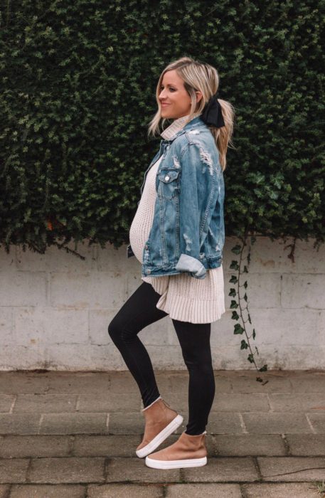 Chica usando un outfit de maternidad de leggins, bluson, tenis y chaqueta de mezclilla 