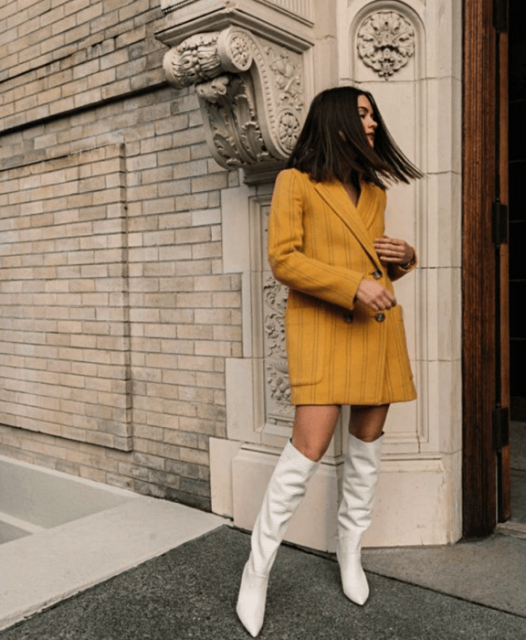 chica morena con blazer oversized amarillo y botas largas blancas de cuero