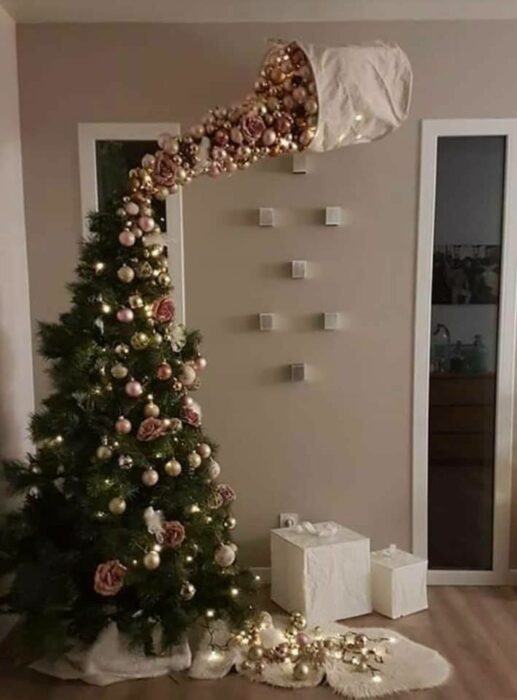 Pinito navideño decorado con esferas doradas cayendo de un saco; ideas para decorar tu arbolito de Navidad