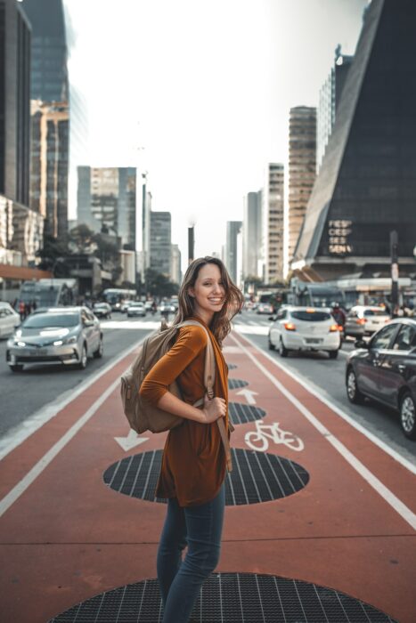 Chica caminando por una ciclovía de la ciudad cargando una mochila en los hombros