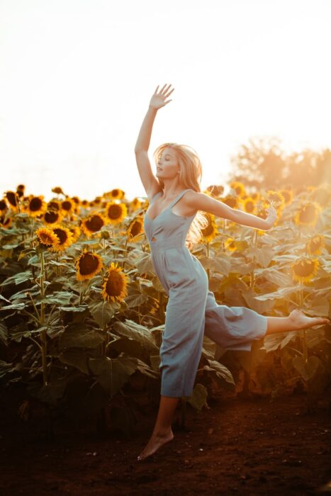 Chica bailando en un campo de girasoles gigantes