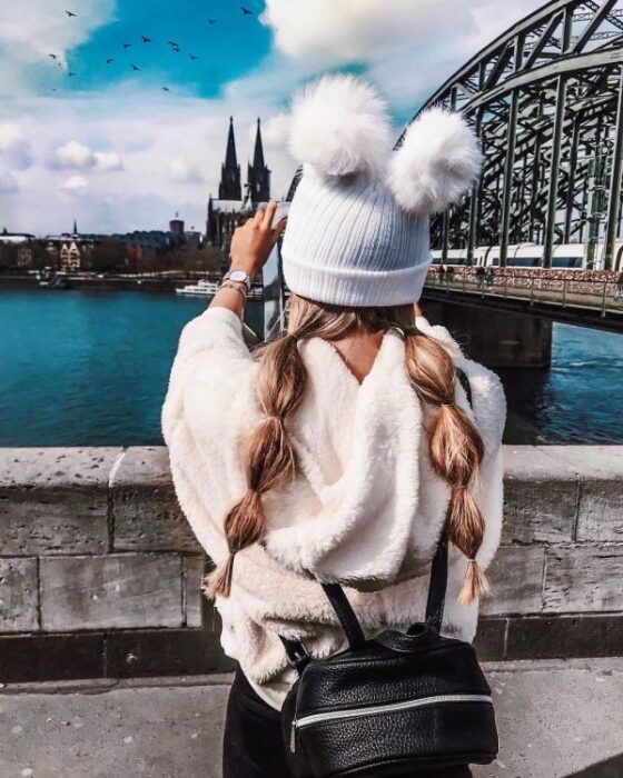 Chica llevando gorro con doble pompón en color blanco ; ideas para llevar gorros y sombreros en otoño