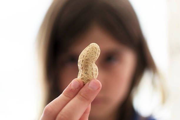 chica sosteniendo un cacahuate entre sus dedos