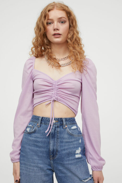 Chica con un una blusa de color morado con jeans 