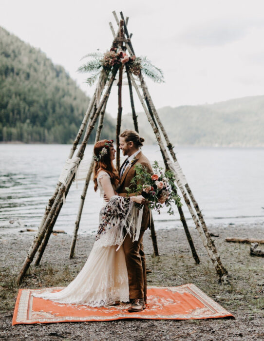 Ideas para una boda vikinga; pareja de novios a la orilla de lago en un altar de madera con flores