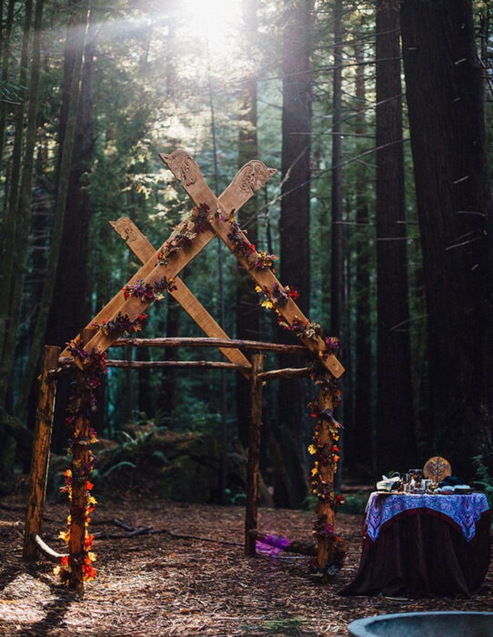 Ideas para una boda vikinga; altar de madera con flores en el bosque