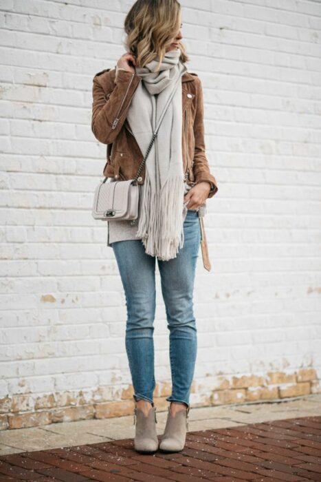 Chica usando bufanda larga de color gris, jeans y chaqueta camel